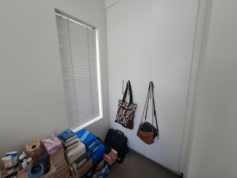 A bedroom featuring a built-in wardrobe with white doors and a window fitted with venetian blinds.