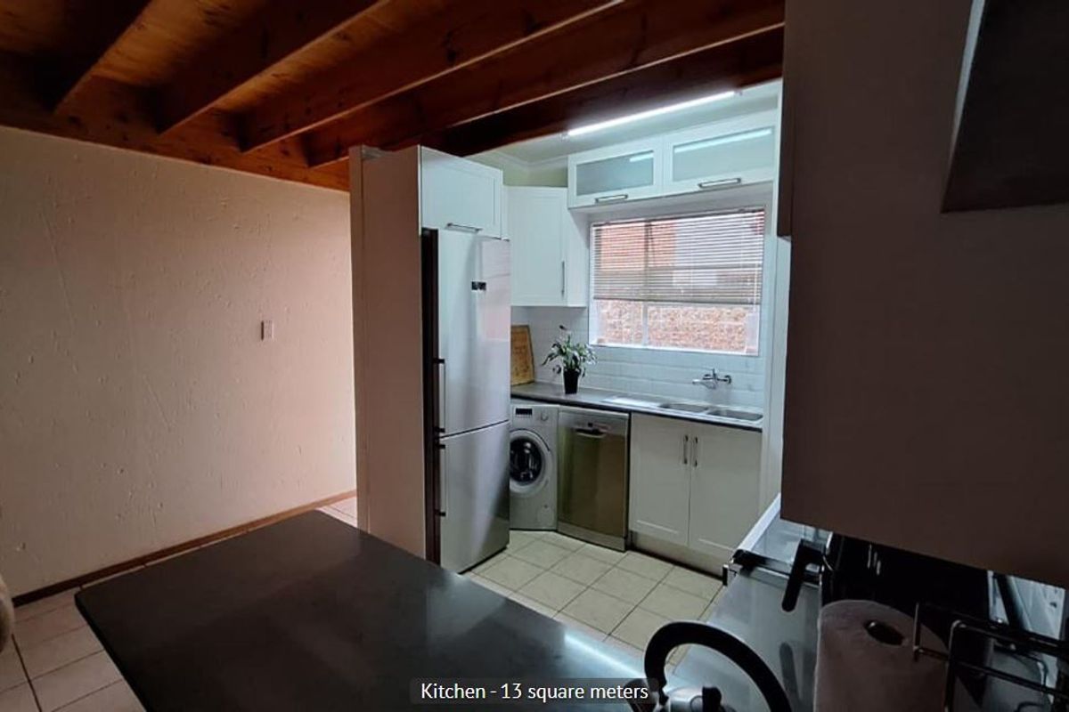 A functional kitchen featuring exposed timber ceiling beams, white cabinetry, subway tile backsplash, and tiled flooring, providing a practical workspace.