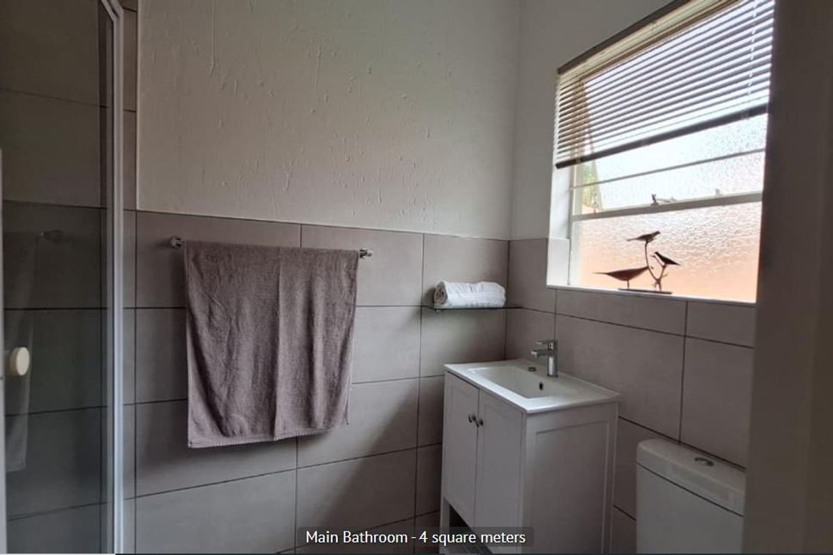 A functional main bathroom featuring a shower enclosure, vanity basin, and toilet with neutral wall tiling.