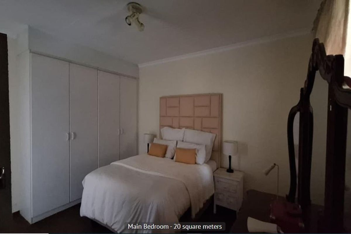 A spacious main bedroom featuring built-in cupboards and neutral wall finishes, offering a comfortable and functional living space.