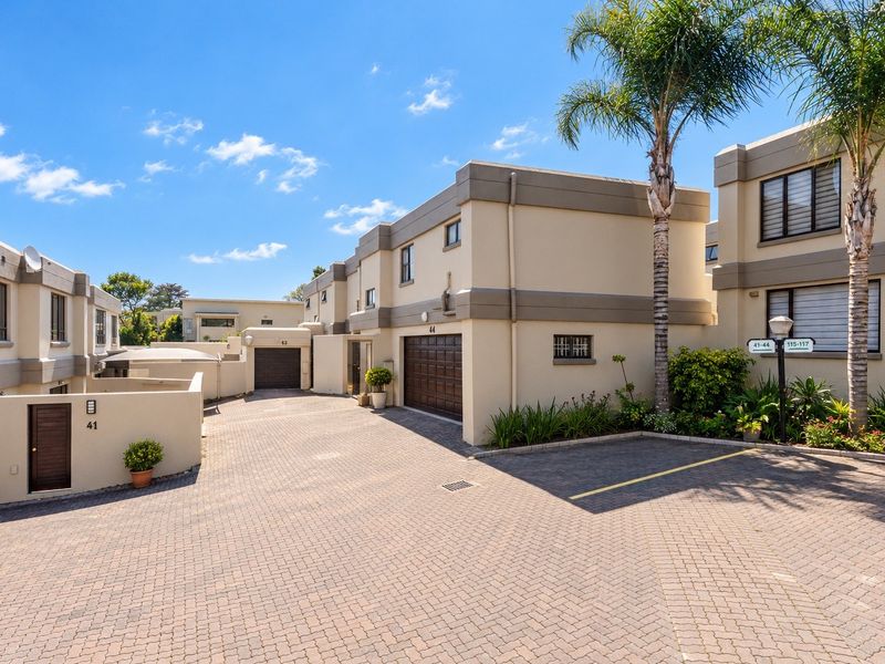 A view of the paved driveway and front facades of the cluster units, featuring secure garage access and well-maintained exterior walls.