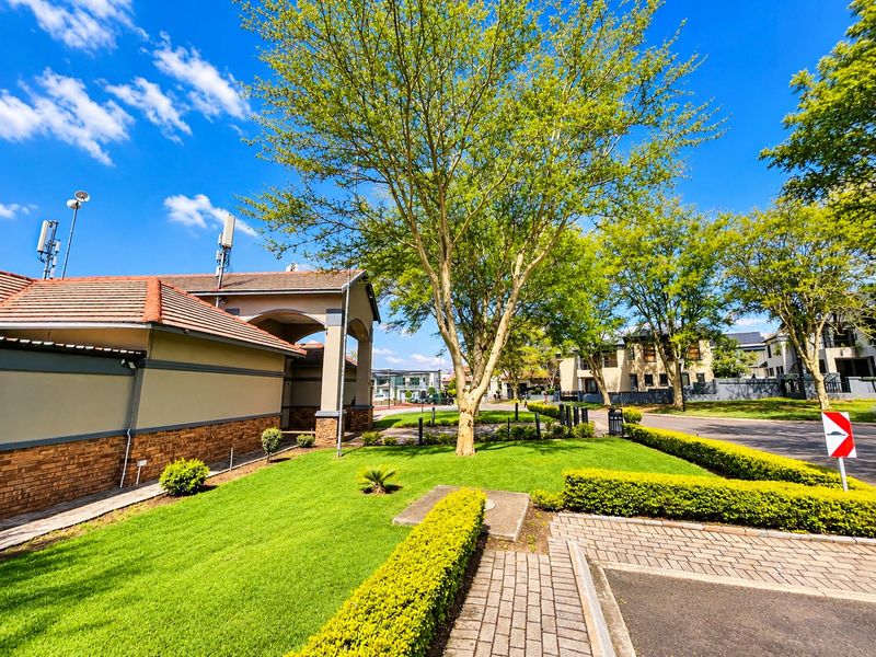 A well-maintained residential exterior featuring a landscaped garden, paved driveway, and brick facade with a tiled roof in a suburban setting.
