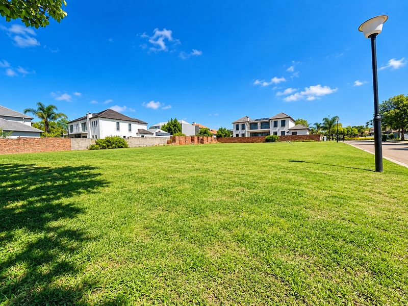 A vacant residential plot featuring a well-maintained lawn, enclosed by brick boundary walls, situated in a developed neighborhood with street lighting.