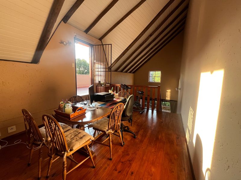 A loft-style office space featuring exposed timber ceiling beams, warm timber flooring, and a timber balustrade overlooking the lower level.