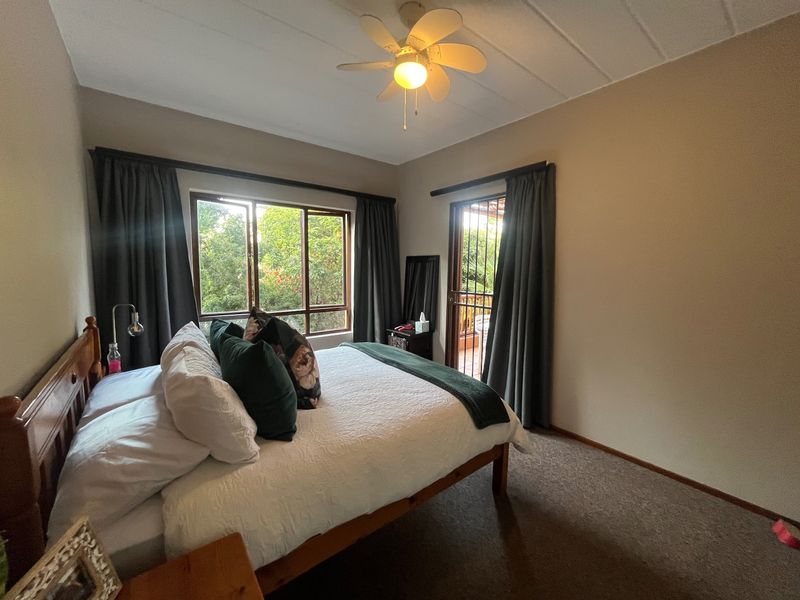 A bedroom featuring a ceiling fan, carpeted flooring, and direct access to a balcony through a sliding door.
