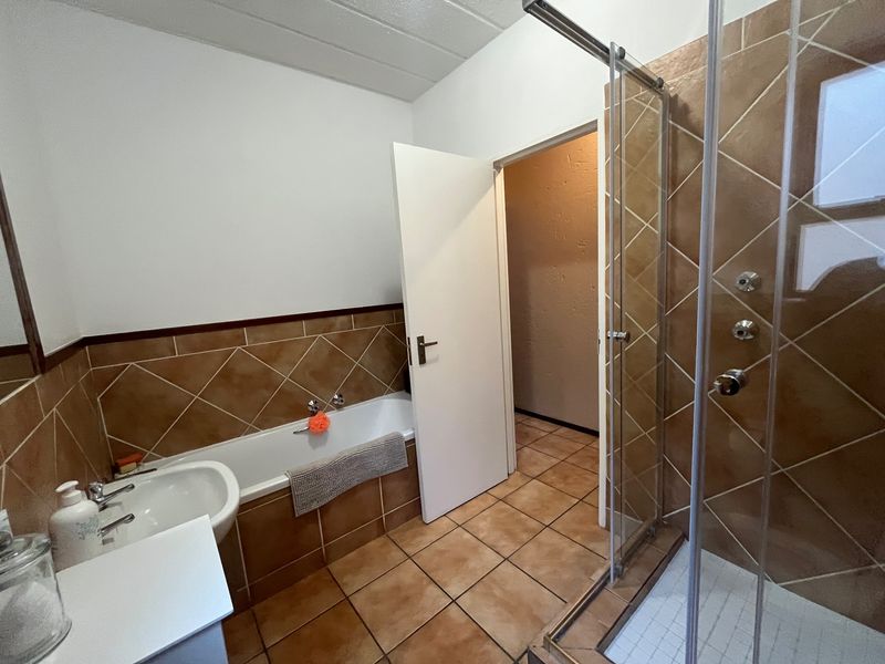 A functional bathroom featuring a bathtub, separate shower enclosure, and tiled finishes throughout.