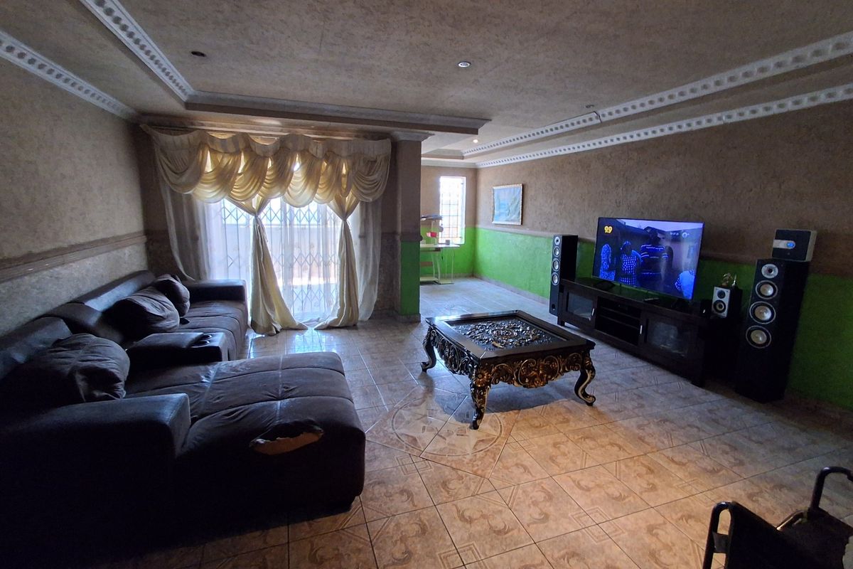Spacious living room featuring tiled flooring, decorative ceiling cornices, and recessed lighting, offering a comfortable area for relaxation and entertainment.