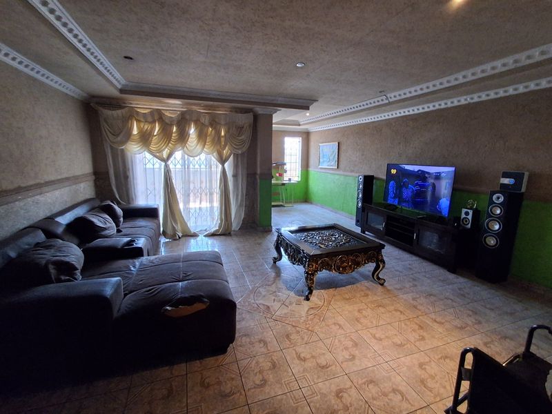 Spacious living room featuring tiled flooring, decorative ceiling cornices, and recessed lighting, offering a comfortable area for relaxation and entertainment.
