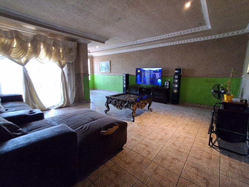 Spacious living room featuring tiled flooring, recessed ceiling lighting, and decorative cornicing, offering a versatile layout for comfortable family living.
