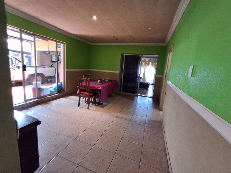 Spacious living area featuring tiled flooring, coved ceilings, and large sliding glass doors providing access to the exterior.