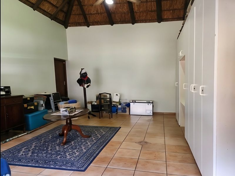 Spacious bedroom featuring a high vaulted thatched ceiling with exposed timber beams, tiled flooring, and extensive built-in cupboard storage.