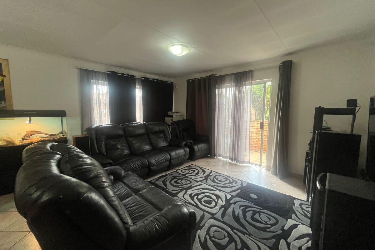 A spacious living room featuring tiled flooring and a sliding glass door providing access to the outdoor area.