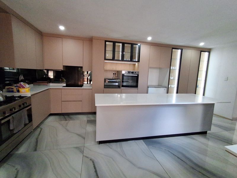 Modern kitchen featuring sleek cabinetry, a central island with stone countertops, integrated appliances, and large format marble-look floor tiles.