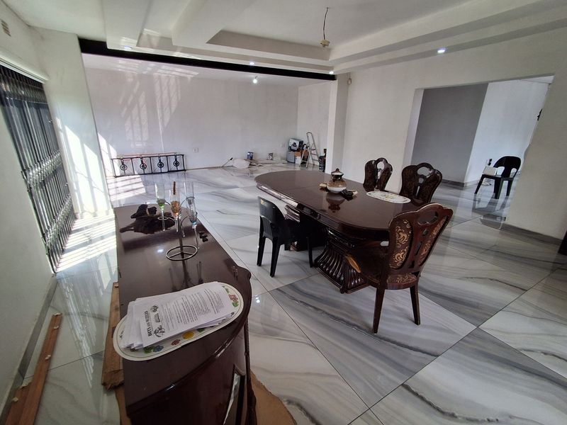 Spacious dining area featuring large-format marble-look floor tiles and a recessed ceiling design, offering a bright and open layout for entertaining.