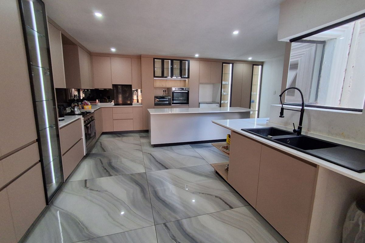 Modern, spacious kitchen featuring sleek cabinetry, a large central island, high-end integrated appliances, and premium marble-effect porcelain floor tiles.
