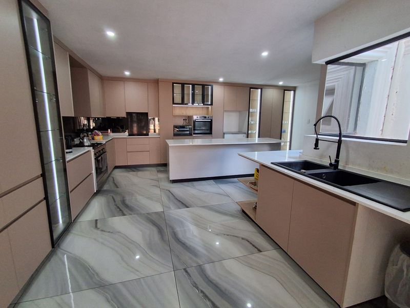 Modern, spacious kitchen featuring sleek cabinetry, a large central island, high-end integrated appliances, and premium marble-effect porcelain floor tiles.