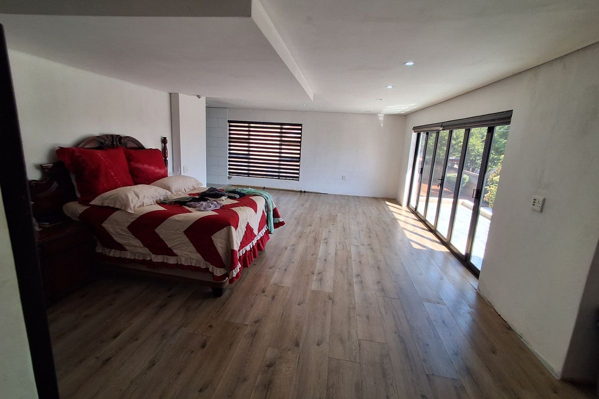 Spacious bedroom featuring modern laminate flooring, recessed ceiling lights, and large sliding glass doors providing ample natural light and access to the exterior.