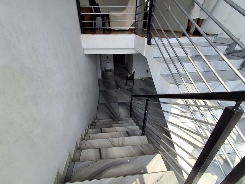 A modern staircase featuring large-format marble-look tiles and a sleek metal balustrade, connecting two levels of the home.