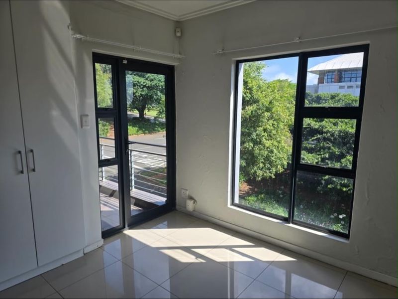 Bright and airy bedroom featuring tiled flooring, built-in cupboards, and direct access to a private balcony through an aluminium door.