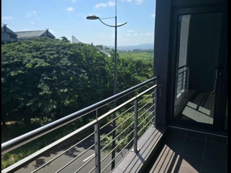 A clean, modern balcony featuring tiled flooring and a stainless steel balustrade, offering an elevated view of the surrounding area.