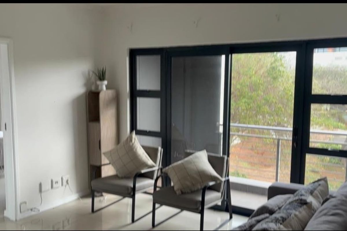 A bright living room featuring large sliding glass doors that open onto a balcony, providing natural light and outdoor access.
