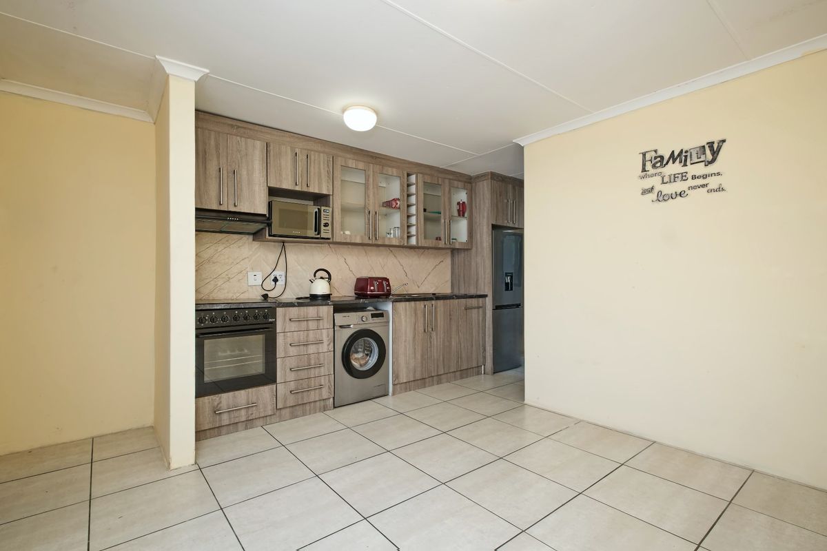 Functional kitchen featuring wood-look cabinetry, tiled flooring, built-in oven with hob, and integrated microwave space, offering a practical layout for daily cooking.