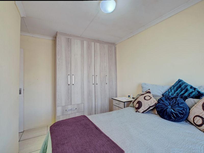 A functional bedroom featuring light wood-finish built-in wardrobes and tiled flooring, offering a neutral base for personalization.