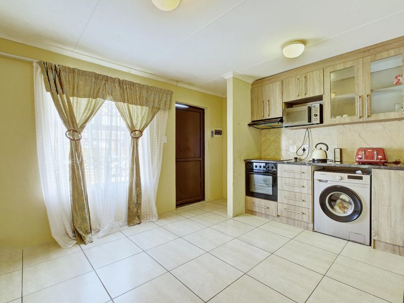 A functional kitchen featuring light wood-finish cabinetry, tiled flooring, built-in oven with extractor, and integrated microwave space, offering a practical layout for daily use.