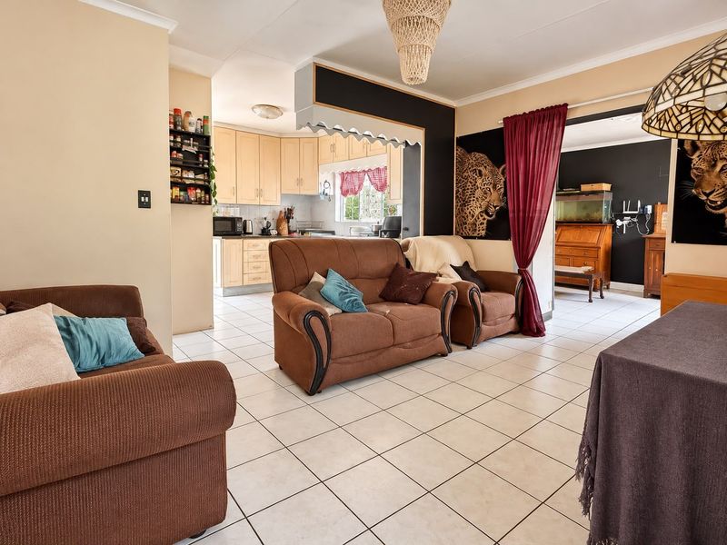 Open plan living area featuring ceramic floor tiles and a connected kitchen with built-in cabinetry, creating a functional and integrated living space.