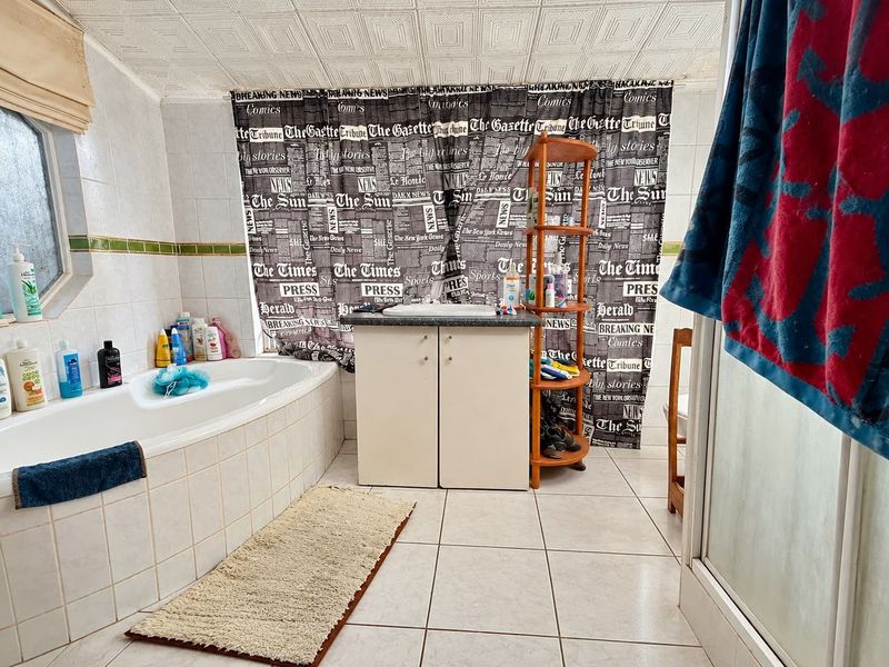 A dated bathroom featuring a built-in bathtub, tiled vanity, and ceramic flooring, offering significant potential for modernization and renovation.