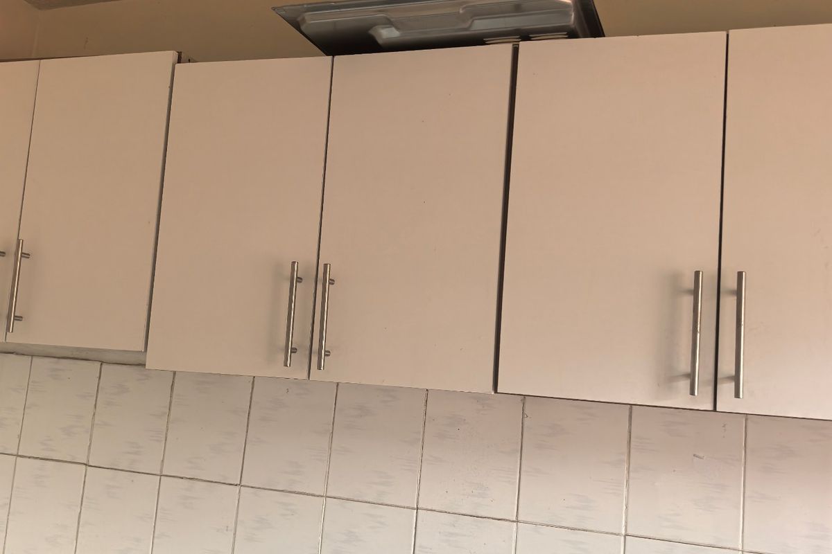 A kitchen area featuring white cabinetry, a tiled backsplash, and a stone countertop, showing signs of incomplete installation and wear.