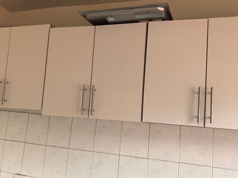 A kitchen area featuring white cabinetry, a tiled backsplash, and a stone countertop, showing signs of incomplete installation and wear.