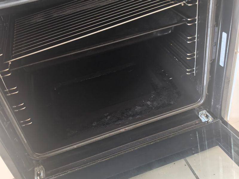 A close-up view of a built-in oven showing significant interior grease and carbon residue on the base.