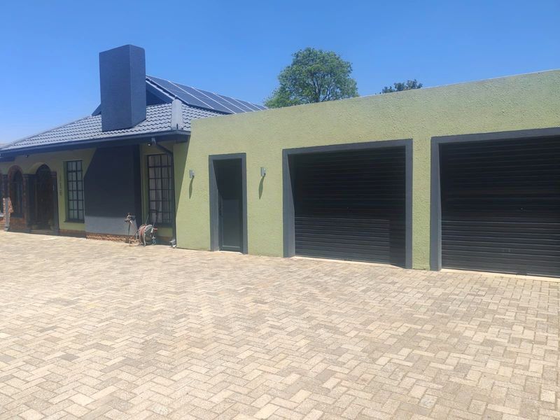 Front view of the property featuring a paved driveway, double garage, and solar panels installed on the tiled roof.