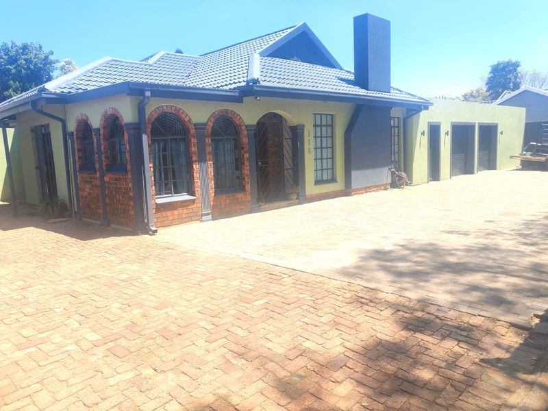 Front elevation of a house featuring a brick paved driveway, tiled roof, and distinctive arched window detailing with integrated garage access.