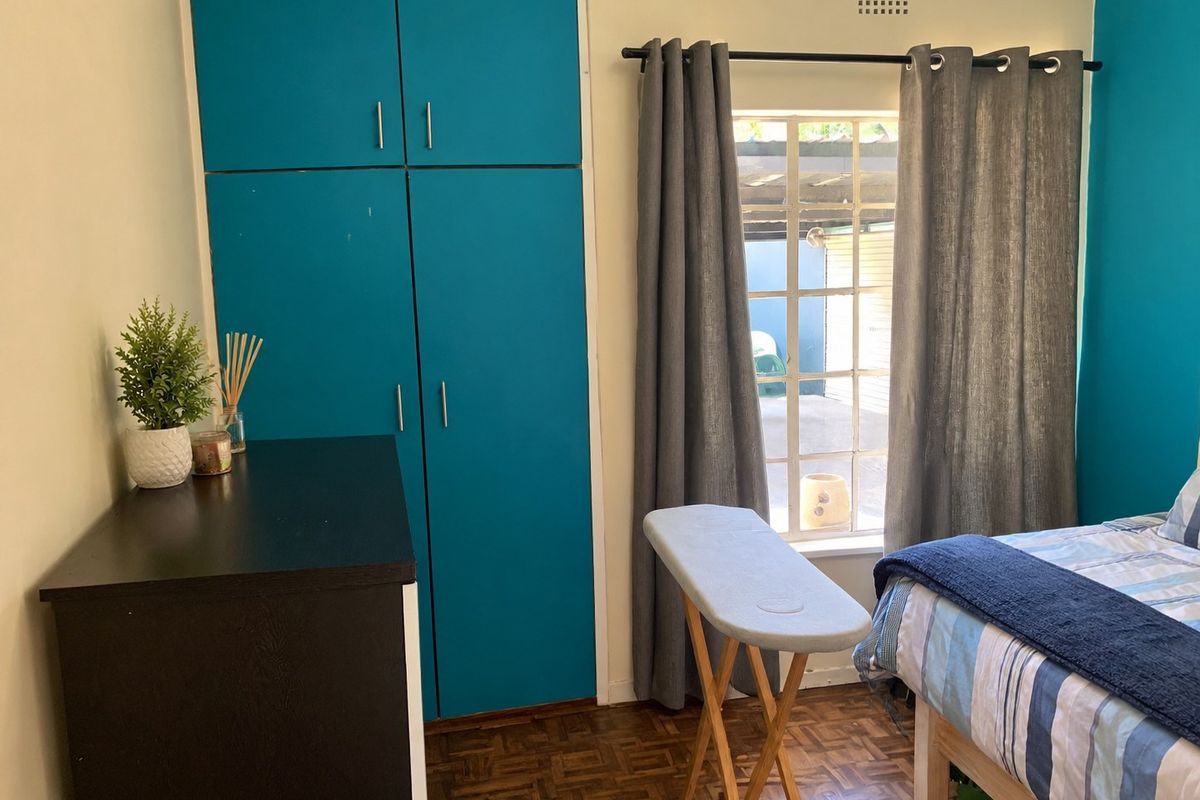 A bedroom featuring parquet flooring and built-in cupboards with a window providing natural light.