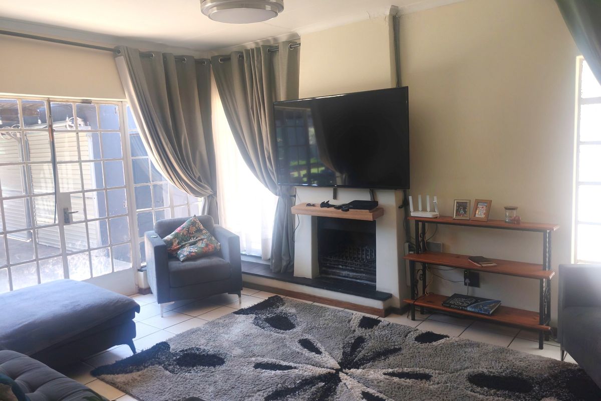 A comfortable living room featuring a built-in fireplace, tiled flooring, and direct access to the outdoor area through glass-paned french doors.