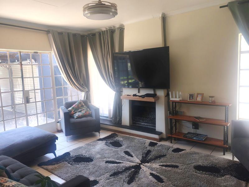 A comfortable living room featuring a built-in fireplace, tiled flooring, and direct access to the outdoor area through glass-paned french doors.