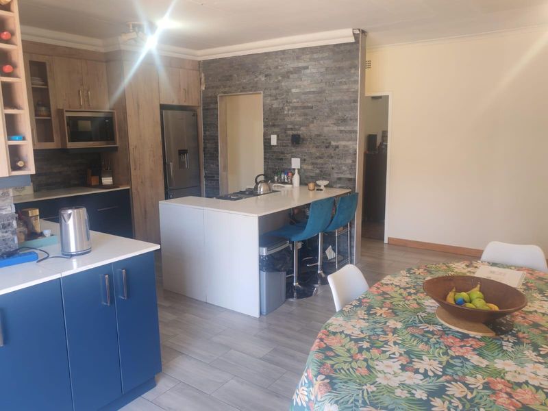 Open plan kitchen featuring a stone veneer accent wall, modern cabinetry, and a central island with breakfast bar seating.