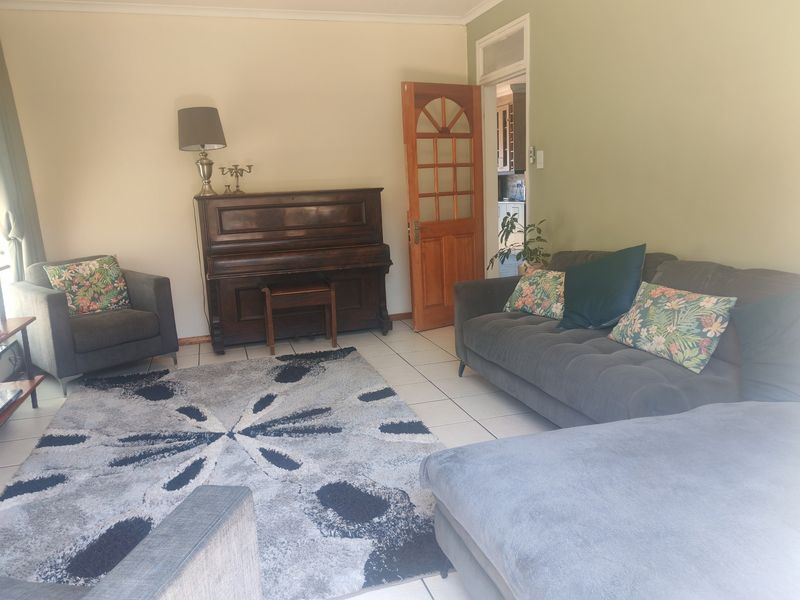A comfortable living room featuring tiled flooring and a classic timber door with glass panels, providing access to the adjacent kitchen area.