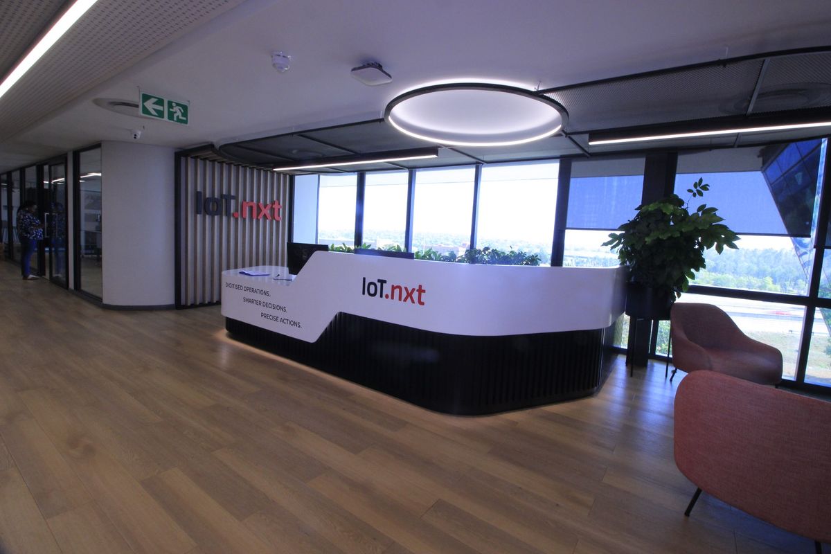 Modern commercial reception area featuring a sleek custom desk, wood-look flooring, and expansive windows providing natural light and views.