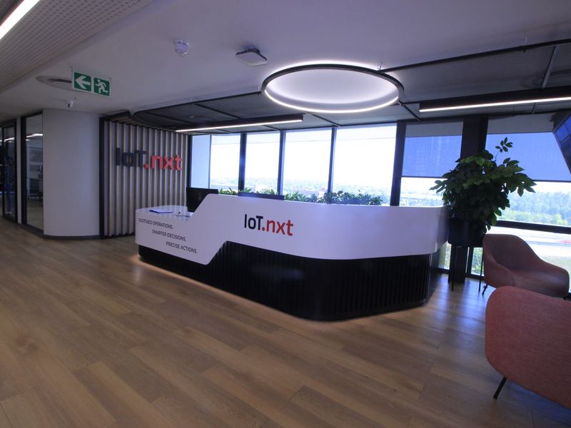 Modern commercial reception area featuring a sleek custom desk, wood-look flooring, and expansive windows providing natural light and views.