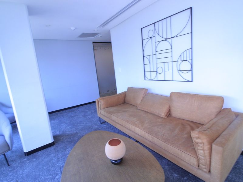 A modern commercial lounge area featuring neutral carpeting, recessed ceiling lighting, and integrated air conditioning, providing a professional and comfortable waiting space.
