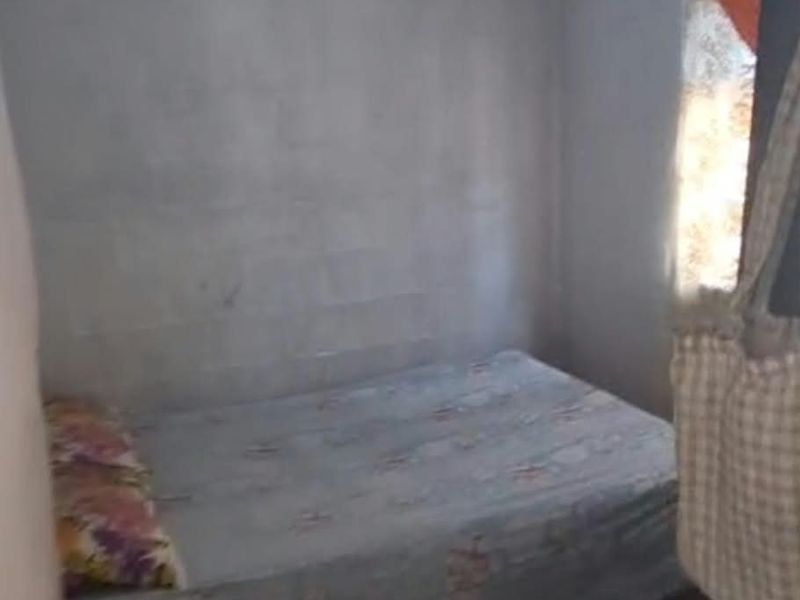 A small bedroom featuring exposed concrete block walls and an unfinished ceiling, requiring cosmetic updates to improve the living space.