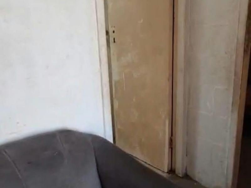 A narrow hallway area featuring a standard internal door and worn wall finishes, requiring cosmetic updates and maintenance.