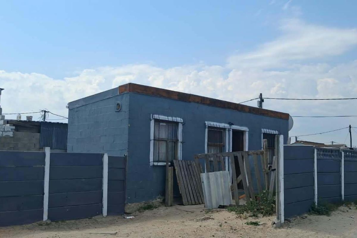 Front exterior view of a single-story residential property featuring concrete block construction, a flat roof, and a perimeter boundary wall.