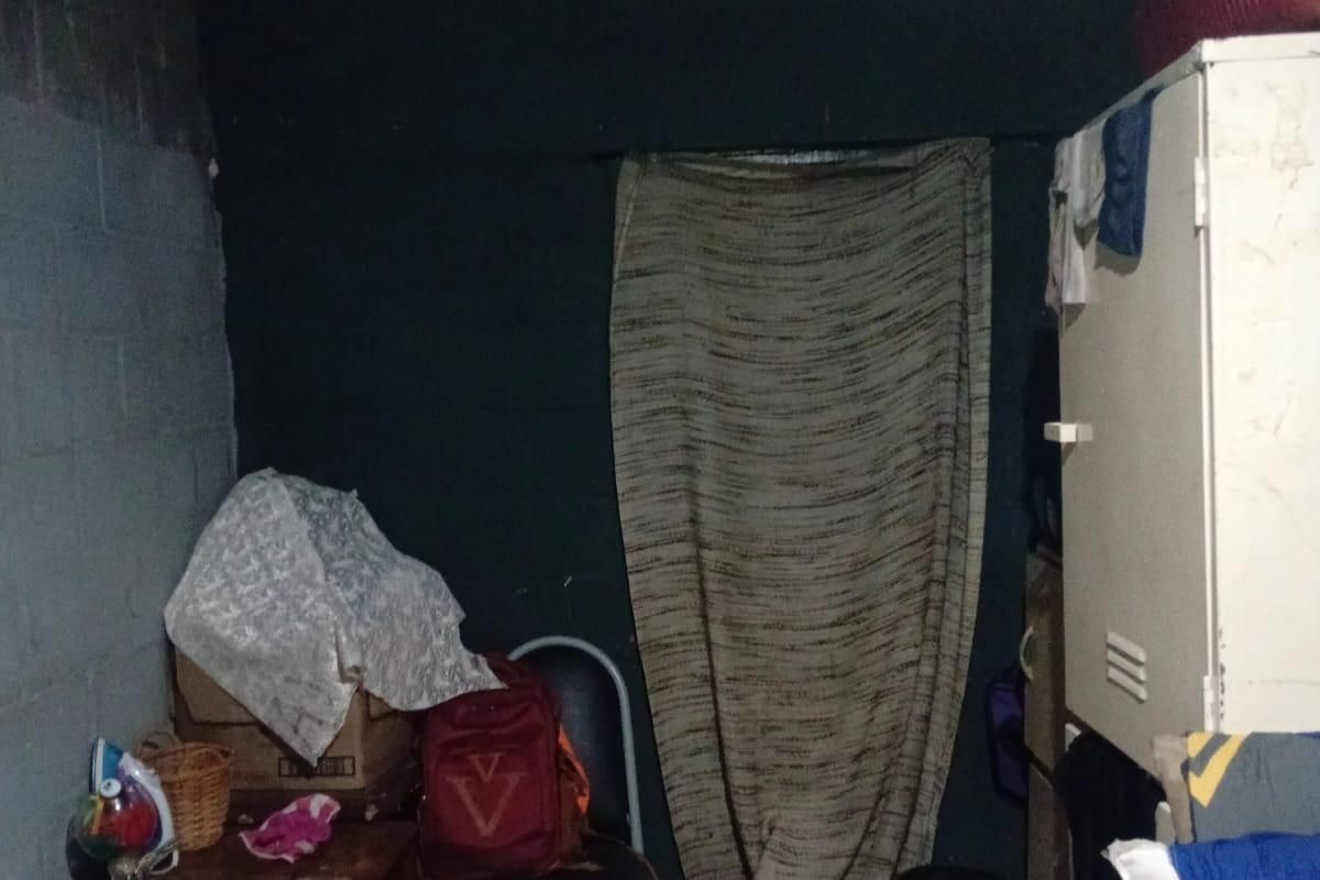 A small, dimly lit room with unfinished walls and exposed ceiling structure, currently used for storage.