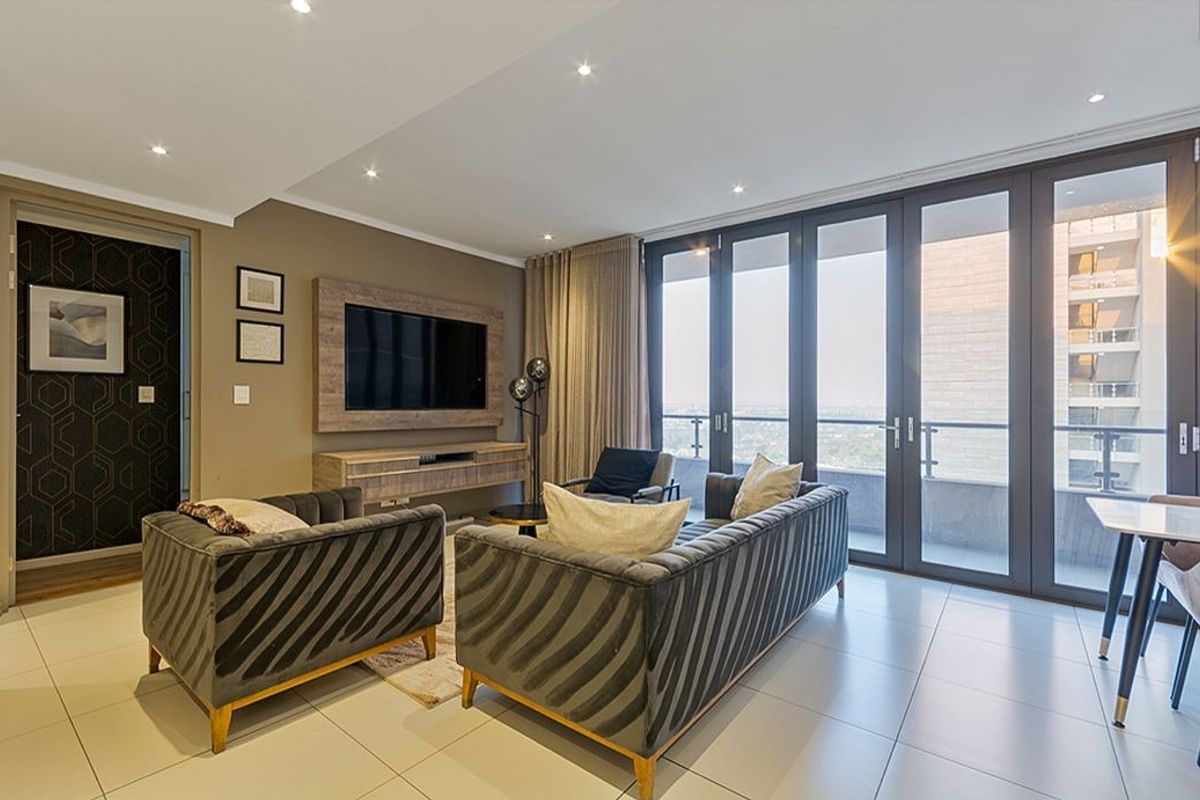 Modern living room featuring tiled floors, recessed lighting, and large glass sliding doors leading to a balcony with an urban view.
