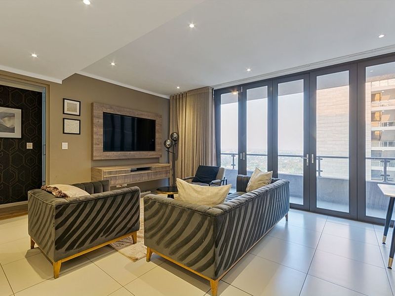 Modern living room featuring tiled floors, recessed lighting, and large glass sliding doors leading to a balcony with an urban view.