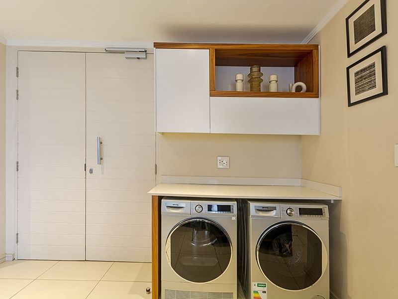 A clean and functional laundry area featuring built-in cabinetry, a solid countertop, and space for side-by-side appliances.